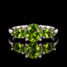 The same VooDooStone three-stone ring turning peridot green under fluorescent light, front view. Item 894786.