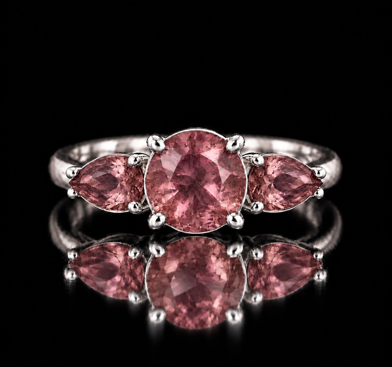 Sterling silver VooDooStone three-stone ring, round center stone with pear side stones, all purplish-pink in daylight, front view. Item 894786.