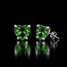 The same VooDooStone heart-cut stud earrings turning peridot green under fluorescent light. Item 894788.